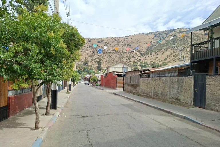 Calle residencial con árboles y cerros al fondo.