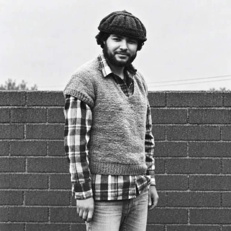 Retrato en blanco y negro de un hombre con gorro de lana, camisa a cuadros y chaleco.